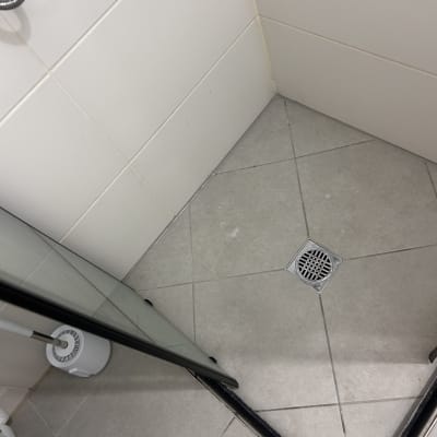 פינת מקלחת עם רצפת אריחים וניקוז