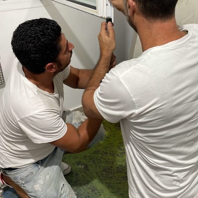 שני אנשים מתקנים תריסים עם כלים