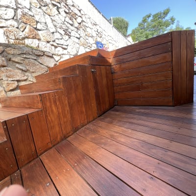 דק עץ חום עם מדרגות ליד קיר אבן