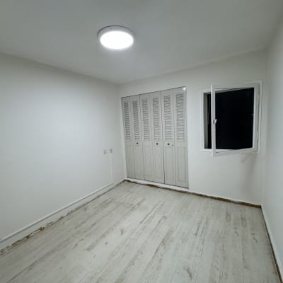 חדר צבוע בלבן עם חלון פתוח ודלת סגורה