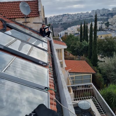 אדם יושב על גג עם ציוד להסרת יונים