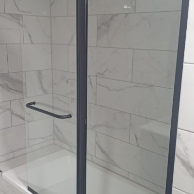 מקלחון עם דלת זכוכית ומסגרת מתכת שחורה