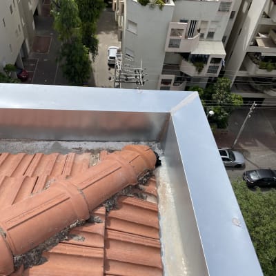 גג רעפים אדומים עם צינור חרסית ופס מתכת