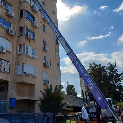 מנוף שיפוצים ליד בניין גבוה עם פועלים