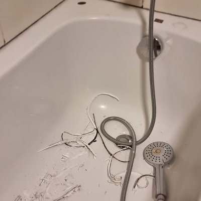 אמבטיה עם שאריות חומר ושפופרת מקלחת