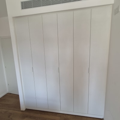 ארון בגדים לבן עם דלתות עץ על רצפת עץ