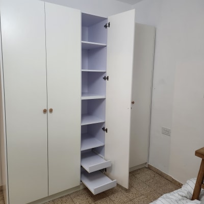 ארון בגדים עם דלתות פתוחות ומגירות בחדר שינה