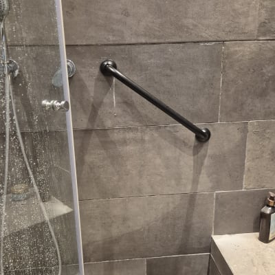 מקלחת עם מוט אחיזה על קיר אריחים אפורים