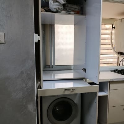 מכונת כביסה בתוך ארון במטבח עם מדפים פתוחים