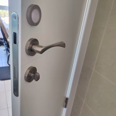 ידית דלת מתכתית עם מנעול על דלת לבנה