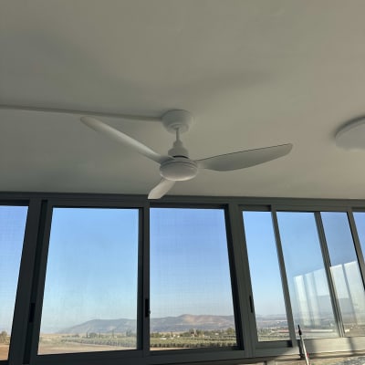 מאוורר תקרה בחדר עם חלונות גדולים ונוף חיצוני