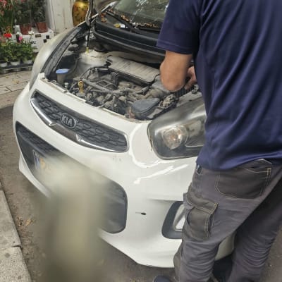 אדם מתקן מנוע של רכב עם מכסה פתוח