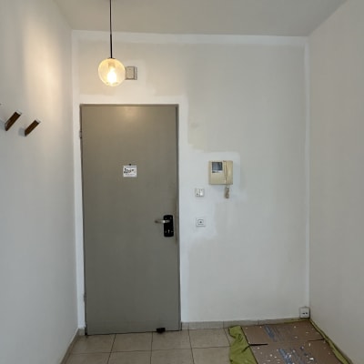 דלי צבע ומברשת על רצפה ליד דלת