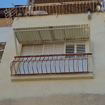 מרפסת עם סורגים ומזגן על קיר חיצוני של בניין