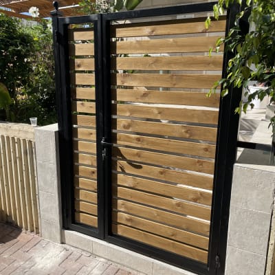 שער עץ עם מסגרת מתכת שחורה בגינה