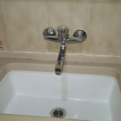 ברז מים מעל כיור לבן עם אריחים