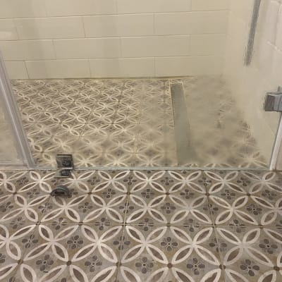 מקלחון עם רצפת אריחים מעוצבת ודלת זכוכית
