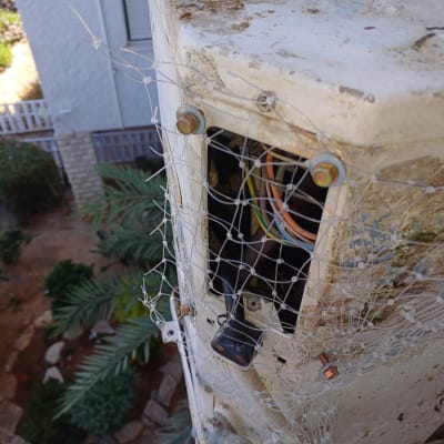 רשת מתכת על תיבת חשמל עם חוטים חשופים