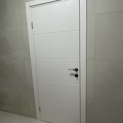 דלת לבנה עם ידית מתכת על קיר אפור