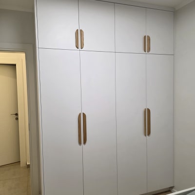 ארון בגדים לבן עם ידיות עץ בחדר שינה