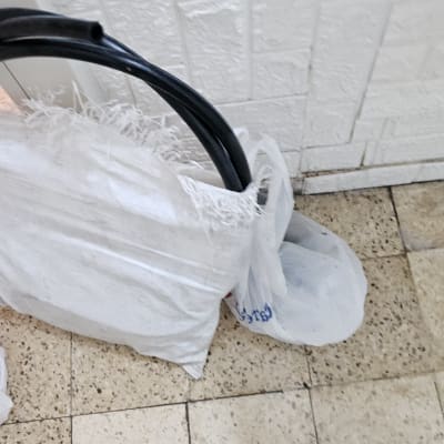 צינור שחור ליד שקית לבנה על רצפה