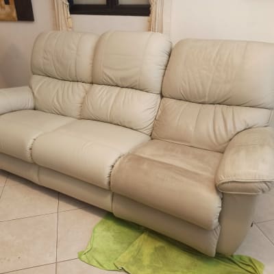 ספה בהירה עם כתם נקי ומטלית ירוקה על הרצפה