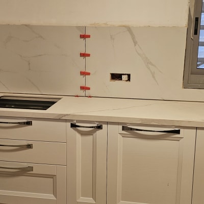 מטבח חדש עם ארונות לבנים ומשטח עבודה שיש.