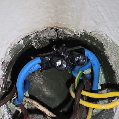 חוטי חשמל צבעוניים מחוברים לקופסת חיבורים בקיר