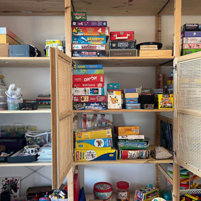 משחקי קופסה מאורגנים על מדפים בארון עץ פתוח