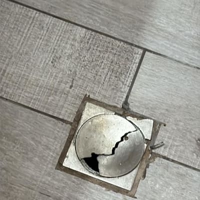 פתח ניקוז שבור ברצפת אריחים אפורה