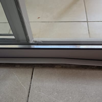 תמונת תקריב של מסילת חלון הזזה מאלומיניום ואטום סיליקון בחלקו התחתון