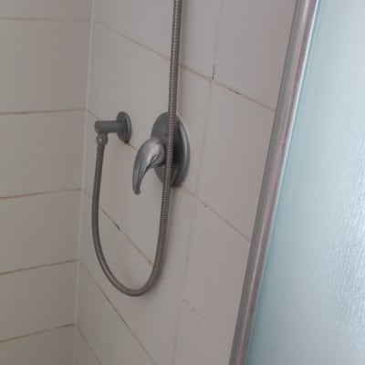 ברז מקלחת עם צינור מתכת על קיר אריחים