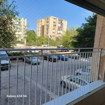 רשת הגנה על מרפסת עם נוף לבניינים ועצים