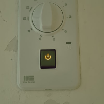 תרמוסטט עם כפתור הפעלה מואר על קיר