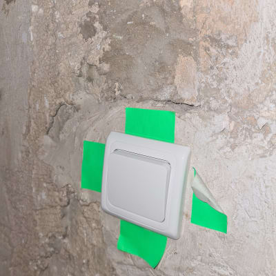 מתג חשמל על קיר עם סרט דבק ירוק