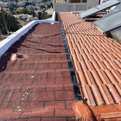 גג עם רעפים אדומים וקולטי שמש