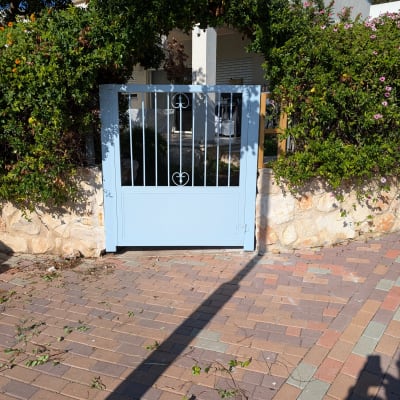 שער מתכת כחול מוקף בצמחייה ירוקה