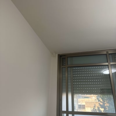 קיר ותקרה צבועים בלבן ליד חלון