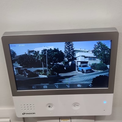 מסך אינטרקום מציג נוף חיצוני עם מכוניות ובניינים