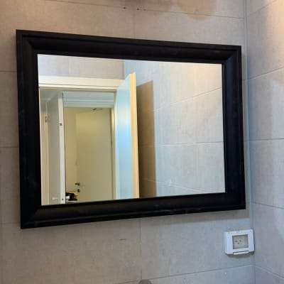 מראה עם מסגרת שחורה, כיור וברז, פטיש על השיש