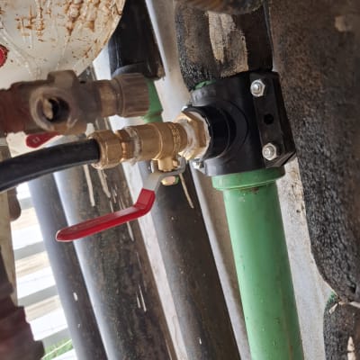 שסתום פליז עם ידית אדומה על צינור ירוק