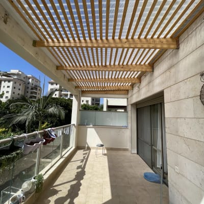 פרגולה מעץ עם קורות עץ על מרפסת