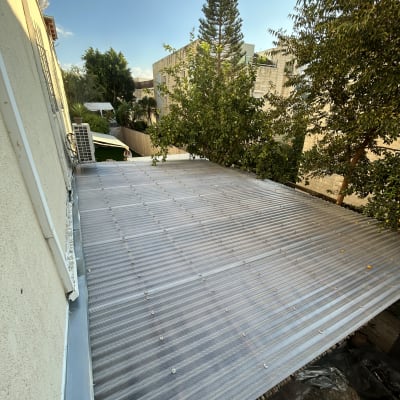 גג מתכת בחצר עם עצים מסביב