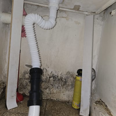 צינור ניקוז מתחת לכיור עם סימני רטיבות ועובש