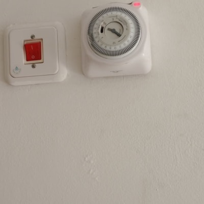 מתג ושעון טיימר על קיר לבן