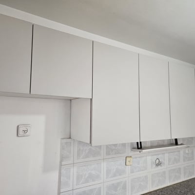 ארונות מטבח לבנים על קיר עם אריחים