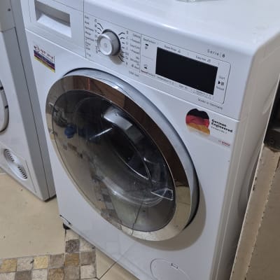 מכונת כביסה בוש עם צינור פליטה ודלי על המכסה