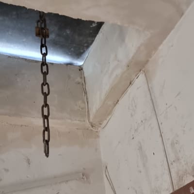 שרשרת מתכת תלויה מהתקרה ליד דלת עץ