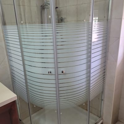 מקלחון זכוכית עם דלתות מעוגלות וראש מקלחת