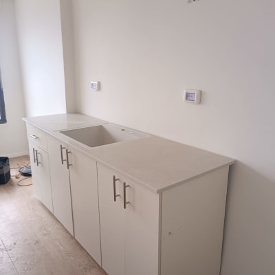 משטח שיש בהיר על ארונות מטבח לבנים